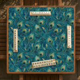 A teal mahjong mat with a peacock feather pattern and scalloped edges.