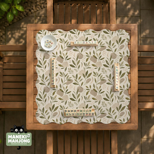 Green botanical mahjong mat with sage leaf and floral design and a scalloped edge.